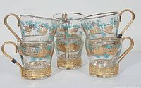Front view showing all six matching beverage mugs with turquoise and gold pine cone motif and gold handles.