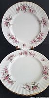 Front view of two Royal Albert bone china salad plates showing pink rose floral pattern with gold rim and scalloped edges.