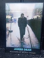 Framed vintage poster featuring James Dean walking on a rainy street with title text at the bottom.