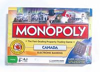 Photo of Monopoly Canada Electronic Banking board game box showing front top view with branding, Canadian cities badge, and electronic banking feature.