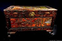 Full view of the large hand carved wooden chest showing Asian motif, dark finish, and solid brass hardware on front.