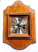 Front view of the vintage Bulova wooden wall mount clock showing the full wooden frame and clock face with Roman numerals.