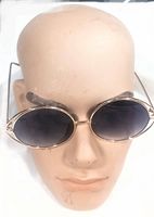 Front view of vintage fashion sunglasses on a mannequin head showing oval dark gradient lenses and gold-tone metal frame.