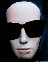 Front view of vintage black rectangular sunglasses on mannequin head to show style and frame shape.