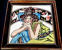 Full view of the framed vintage needlepoint showing a woman seated with colorful background and decorative elements.