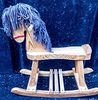 Full side view of the vintage hand carved wooden rocking horse showing the yarn mane, flat seat, and wooden rockers.