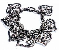 Photo showing vintage heart charm bracelet laid flat with all seven hearts and chain visible.