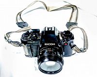 Front angled view of the vintage Ricoh camera showing lens, body, and strap