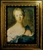 Close-up view of the silk miniature portrait showing the woman in an 18th century style dress with blue fabric detail and the ornate gold frame.