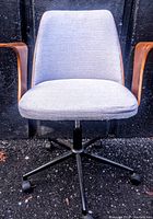 Front view of the office chair showing grey upholstered seat and matching backrest with bentwood armrests and black metal base with casters.