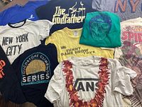 Ten assorted printed t-shirts laid out flat showing different colors, logos and prints to display the variety and condition.