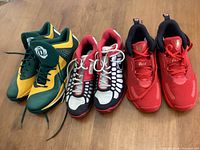 All three pairs of men's athletic shoes placed side by side on floor showing color and style.