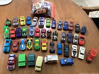 Overview of 44 diecast toy cars arranged on a wooden table, showing variety in style, colors, and types