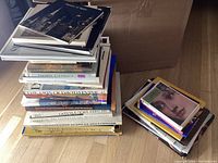 Stack of numerous art books of various sizes and bindings including some vintage editions, with titles visible such as 'Towers of Spice' and 'Tribal Rugs'.
