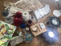 Overview of most items including bookends, mirrors, blue bell, ceramic stein, coasters, watch, lighter, dice cup, candle, and ashtray on table