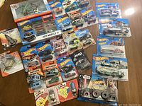 Overview of boxed Hot Wheels, Matchbox cars, Sky Busters airplane toys, and Valentines candy packages on table