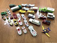 Overview of all 33 diecast vehicles included in the lot with Speed Racer cars, NASA, Tropicana and Toronto trucks, various small vehicles and a winged blue and yellow plane toy.