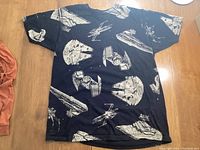 Black T-shirt featuring white spaceship prints such as Millennium Falcon, TIE Fighters, Star Destroyers