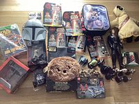 Wide layout of the lot showing packaged Episode I figures, plush Jawa, face mask, Lego set, various small figures and books.