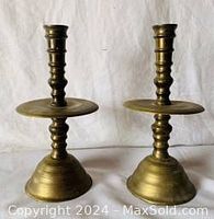 Pair of vintage heavy brass candlesticks with wide drip trays, turned stem design, standing 9 inches tall, shown from front.
