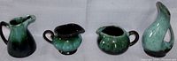 Four Blue Mountain Pottery ceramic pieces in various green shades with spouts and handles on gray background