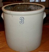 Front view of off-white antique stoneware crock featuring blue number 3 and side lugs.