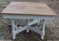 Square antique table with natural finished solid ash top and white painted double trestle base showing turned legs and ornamental gingerbread style supports.