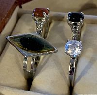 Four ladies rings with various stones displayed in a jewelry box with cream padding.