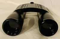 Front view of the black compact binoculars showing objective lenses and textured grip area.