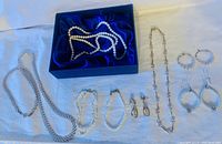 Full set of pearl jewelry including bracelets, necklaces, earrings displayed on white surface and blue satin lined box