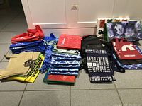 Full view of assorted reusable shopping bags in multiple colors and styles stacked on the floor.