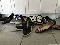 Seven pairs of women's shoes in a line on tiled floor showing overall variety and styles.