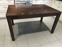 Full view of the dark wood rectangular table with sturdy square legs on tiled floor