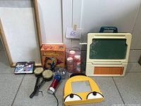Wide shot of the lot showing classroom carrying case, boxed Saxoflute, bongo drums, Etch A Sketch, paint bottles, and whiteboard
