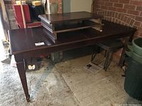 Dark wood extendable table with one extension slid out and showing polished wood surface and sturdy legs.