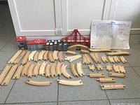 Full layout showing all wooden train track pieces, red bridge, buildings, and supporting parts