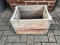 Front view of wooden crate showing faded red Wilson soda branding on wood planks.