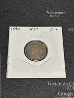 Obverse view of 1890 US Indian Head penny held in a white cardboard holder, showing the head design and '1890' date.