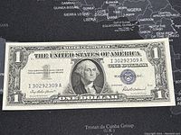 Front side of 1957 US 1 Dollar Silver Certificate banknote showing George Washington portrait and blue seal with serial number.