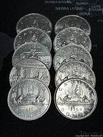 Top view of the coins' reverse side with various designs including the 1967 Confederation commemorative coin and the 1980 coin showing a canoe with two paddlers and large bundles.