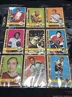 Photo shows nine 1972-73 O-Pee-Chee NHL hockey cards arranged in a grid inside a plastic sleeve with player names and teams visible.
