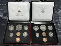Two opened black cases showing 1972 and 1973 Canadian Specimen Coin Sets with seven coins each.