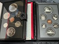 Two open black leatherette cases side by side showing coin layouts for 1976 and 1986 sets