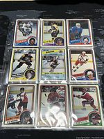Photo of 9 various 1984-85 O-Pee-Chee NHL hockey trading cards in protective sheet showing front player images and teams.