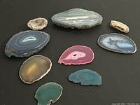 Top view showing all nine assorted agate slices laid out on black background, displaying variety of colors and sizes.