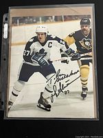 Full view of the autographed 8x10 photo of Darryl Sittler in Toronto Maple Leafs jersey on ice with opposing player.