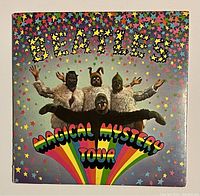 Front cover of the Magical Mystery Tour booklet showing The Beatles in costumes under star design and rainbow text