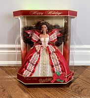 Barbie doll in original packaging standing in clear display box, showing full red and white lace gown with gold accents.