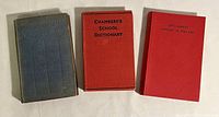 Three old books side by side on white background. From left: faded blue-gray cloth book, Chambers's School Dictionary with red hardcover, and red hardcover Little History of England book.