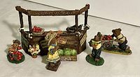 Overview of Bloomenshine's Veggie Mart miniature stand and surrounding miniature bear figures including girl bear and tomato-sitting bear child
